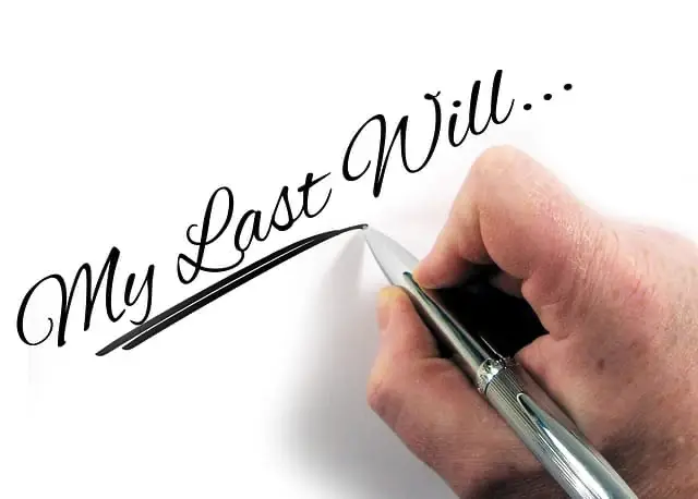 Hand with a pen writing My Last Will on a piece of white paper